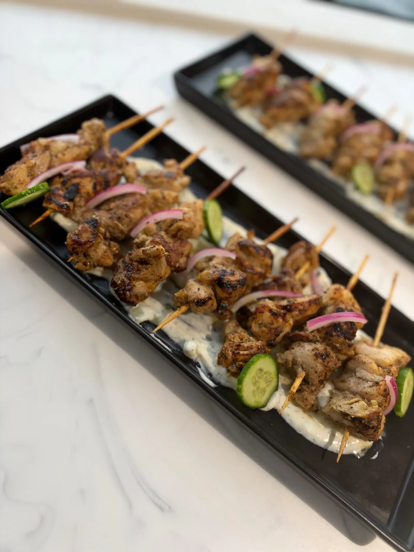 Grilled chicken skewers with herbs and cucumber on a serving platter