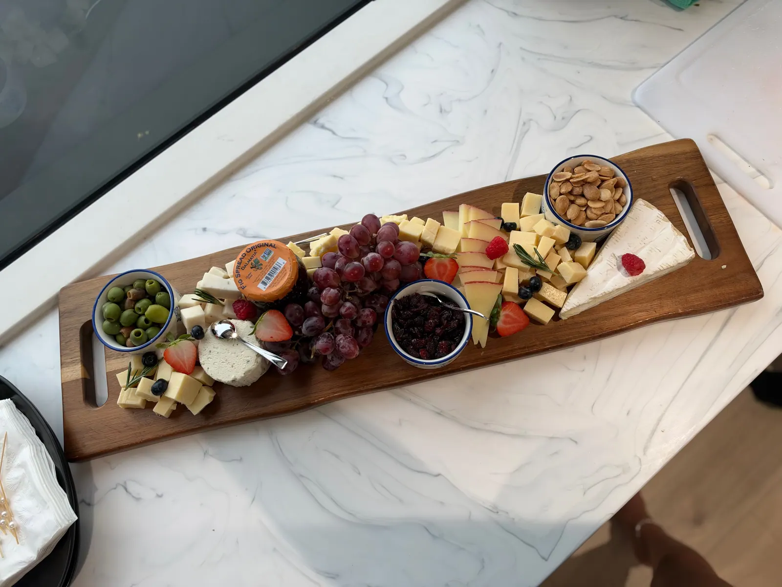 Cheese and fruit grazing board with olives, nuts, and berries