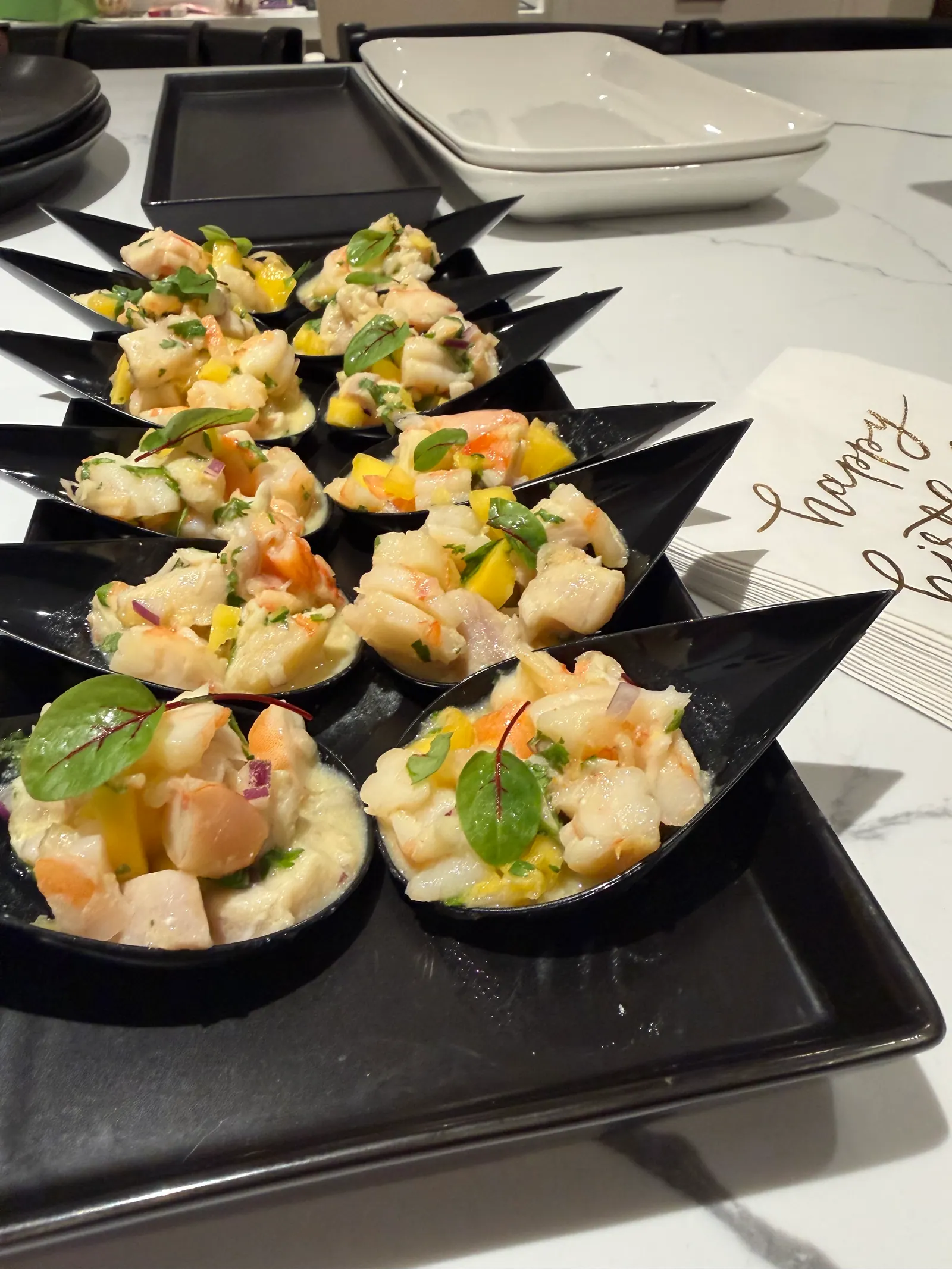 Individual seafood bites served in black tasting spoons